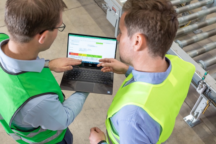 Verpackungsberater der envirogroup steht mit Kunden am Laptop und erklärt wie eine Verbesserung der Klimabilanz durch Stretchfolien Einsparung möglich ist.